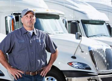 Man standing in front of 2 white 18 wheel trucks