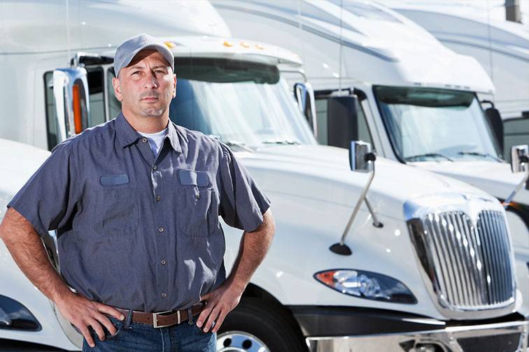 Man standing in front of 2 white 18 wheel trucks