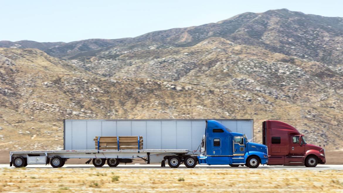 A flatbed and 53' dry van traveling on a highway