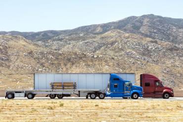 A flatbed and 53' dry van traveling on a highway