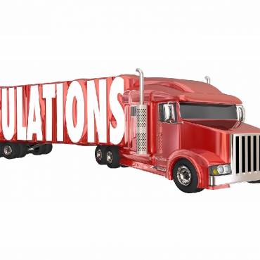 transportation regulations signified by the word regulations on the side of a red 18 wheeler truck