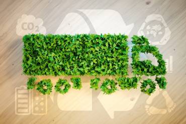 Green truck with recycle logo behind it signifying sustainable trucking practices