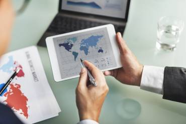 Nearshoring image with people holding a tablet and pointing to transportation ports