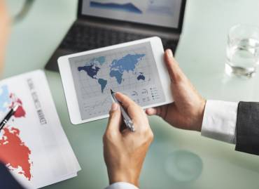 Nearshoring image with people holding a tablet and pointing to transportation ports