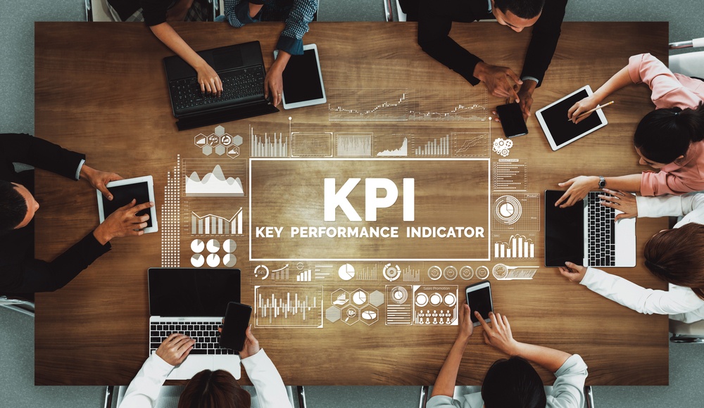 Key performance indicator text with people on their laptops sitting around a table studying warehouse kpis